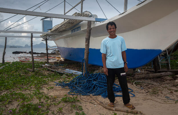 Jonathan in front of the boat carrying 22 people, the broken hull on the ground
